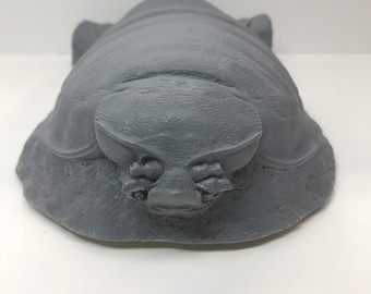 May include: A gray, insect-like sculpture with a textured surface. The sculpture has a rounded body with a segmented head and small, detailed appendages. The overall design suggests a prehistoric or fantasy theme.