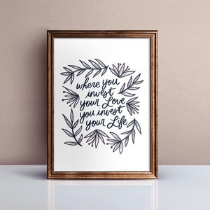 Może przedstawiać: Wydruk w ramie z białym tłem i czarną kaligrafią, kt&oacute;ra brzmi "where you invest your love you invest your life". Kaligrafia jest otoczona wieńcem czarnych i szarych stylizowanych liści i kwiat&oacute;w.