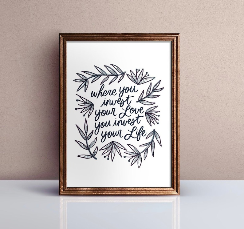 Może przedstawiać: Wydruk w ramie z białym tłem i czarną kaligrafią, kt&oacute;ra brzmi "where you invest your love you invest your life". Kaligrafia jest otoczona wieńcem czarnych i szarych stylizowanych liści i kwiat&oacute;w.