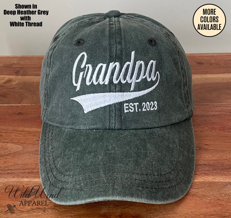 May include: A dark green baseball cap with white embroidery that reads "Grandpa EST. 2023".