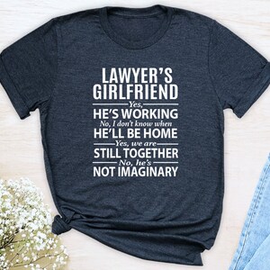 Lawyer&#39;s Girlfriend Yes He&#39;s Working, No I Don&#39;t Know When He&#39;ll Be Home... Unisex T-shirt - Gifts for Lawyer&#39;s Girlfriend