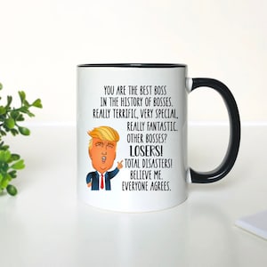 Pode incluir: Caneca de cer&acirc;mica branca com borda e al&ccedil;a pretas. A caneca apresenta uma imagem de desenho animado de Donald Trump com o texto "You are the best boss in the history of bosses. Really terrific, very special, really fantastic. Other bosses? Losers! Total disasters! Believe me. Everyone agrees."