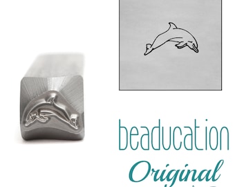 May include: A silver metal stamping tool with a square shaft, featuring a raised dolphin design on the end. Next to the tool is a square inset showing a black line drawing of the same dolphin shape, with the text beaducation Original below.