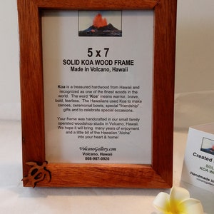 May include: A 5x7 inch solid Koa wood picture frame made in Volcano, Hawaii. The frame is handcrafted and features a carved turtle design in the bottom left corner. The text on the frame reads "Solid Koa Wood Frame Made in Volcano, Hawaii". Koa is a treasured hardwood from Hawaii and recognized as one of the finest woods in the world. The word "Koa" means warrior, brave, bold, fearless. The Hawaiians used Koa to make canoes, ceremonial bowls, special "friendship" gifts and to celebrate special occasions. Your frame was handcrafted in our small family operated woodshop studio in Volcano, Hawaii. We hope it will bring many years of enjoyment and a little bit of the Hawaiian "Aloha" into your heart & home! VolcanoGallery.com Volcano, Hawaii 808-987-0920"