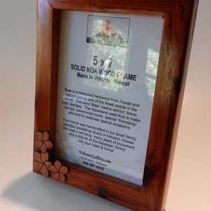 May include: A 5x7 solid Koa wood picture frame made in Volcano, Hawaii. The frame is made of Koa wood, which is a treasured hardwood from Hawaii. The frame is handcrafted in a small family operated woodshop studio in Volcano, Hawaii. The frame is decorated with a carved Koa wood flower design.