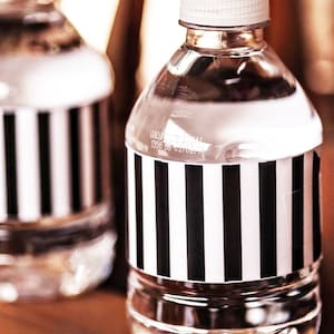 May include: Two clear plastic water bottles with black and white striped labels. The labels have the text "080315141 1356 BB 0270214".