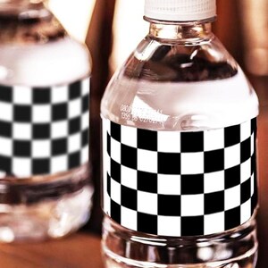 May include: Clear plastic water bottle with a white cap and a black and white checkered label. The bottle is filled with clear liquid. The label wraps around the bottle. The background is blurred.