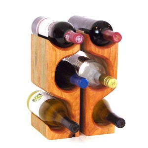 May include: A wooden wine rack with a natural finish, holding six bottles of wine. The rack is constructed with curved openings to cradle the bottles, showcasing a mix of red and white wine.