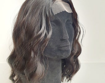 Puede incluir: Peluca ondulada marrón oscuro con frente de encaje, exhibida en una cabeza de maniquí negra. La peluca tiene una línea de cabello de aspecto natural y una apariencia suave y texturizada. El cabello está peinado en ondas sueltas.