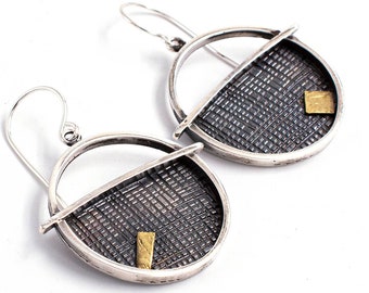 May include: Silver hoop earrings with a textured, black and silver patterned design and a small gold accent.