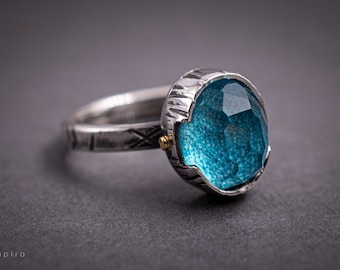 Puede incluir: Un anillo de plata con una banda texturizada y una gran piedra preciosa azul facetada engastada en un engaste de plata.
