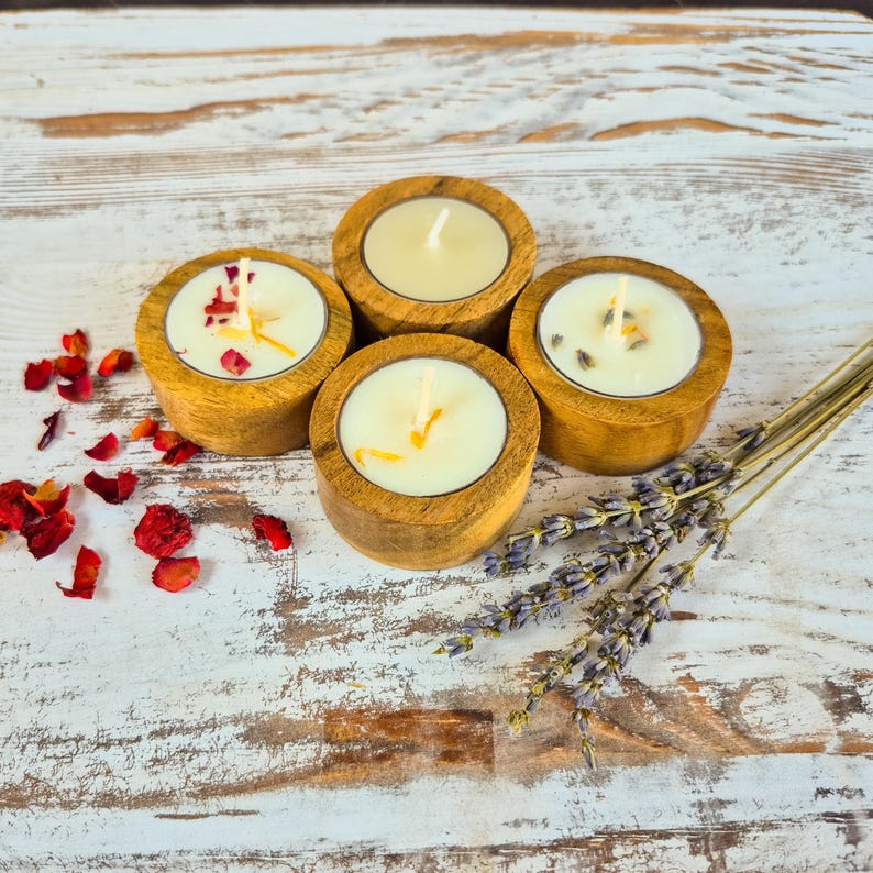 Peut inclure: Quatre bougeoirs en bois pour bougies chauffe-plat avec des bougies allum&eacute;es. Les bougies sont entour&eacute;es de p&eacute;tales de fleurs s&eacute;ch&eacute;es et de brins de lavande. Sur une surface en bois blanc vieilli.