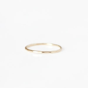 May include: A simple gold band ring with a hammered texture.