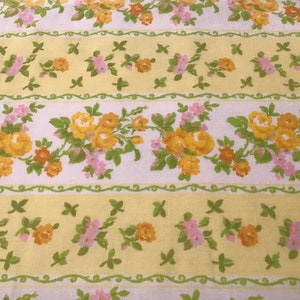 May include: A white fabric with a repeating pattern of yellow and pink flowers on a yellow and white striped background.