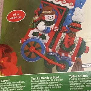 May include: A felt stocking kit featuring a red and blue train with a snowman riding on top. The kit includes felt pieces, embroidery floss, sequins, beads, and instructions. The stocking is 16 inches long.