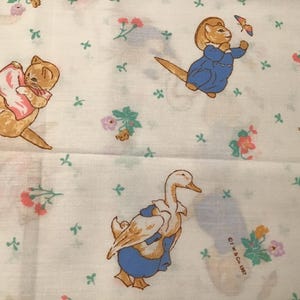 May include: White fabric with a repeating pattern of cartoon animals and floral accents. The illustrations include a cat holding a pink item, a rabbit in blue overalls, and a duck in a blue outfit. Small green cross-shaped designs are scattered throughout.