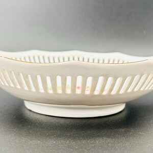 Peut inclure: Un bol en porcelaine blanche avec un bord dor&eacute; et un motif de treillis d&eacute;licat. Le bol a un bord festonn&eacute; et une petite base.