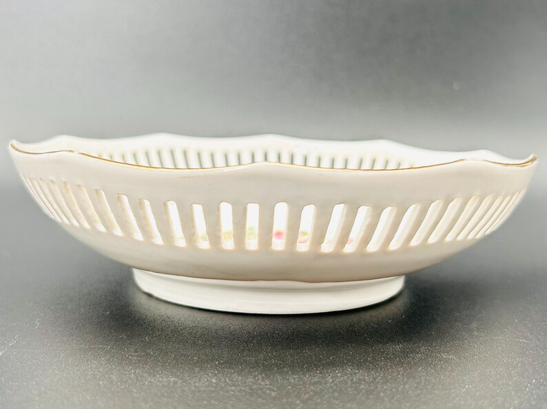 Peut inclure: Un bol en porcelaine blanche avec un bord dor&eacute; et un motif de treillis d&eacute;licat. Le bol a un bord festonn&eacute; et une petite base.