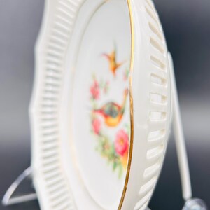 Peut inclure: Une assiette en porcelaine blanche avec un bord festonn&eacute; et une bordure dor&eacute;e. L'assiette pr&eacute;sente un motif floral avec deux oiseaux, un colibri et un faisan.