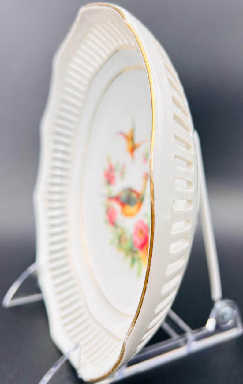 Peut inclure: Une assiette en porcelaine blanche avec un bord festonn&eacute; et une bordure dor&eacute;e. L'assiette pr&eacute;sente un motif floral avec deux oiseaux, un colibri et un faisan.