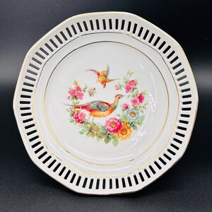 Peut inclure: Assiette en porcelaine blanche avec un bord dor&eacute; et un motif d&eacute;coratif d'oiseaux et de fleurs. L'assiette a un bord festonn&eacute; avec un motif d&eacute;coup&eacute;.