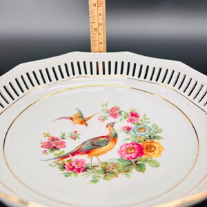 Peut inclure: Bol en porcelaine blanche avec un bord dor&eacute; et un d&eacute;licat motif ajour&eacute; autour du bord. Le bol pr&eacute;sente un motif peint &agrave; la main d'un faisan et d'autres oiseaux entour&eacute;s de fleurs color&eacute;es.