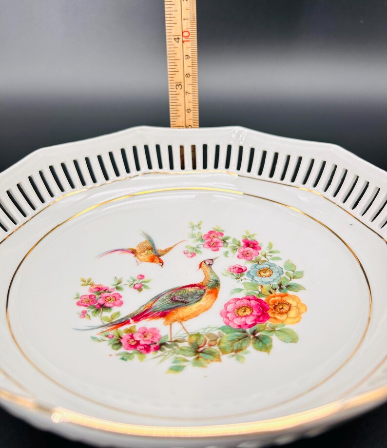 Peut inclure: Bol en porcelaine blanche avec un bord dor&eacute; et un d&eacute;licat motif ajour&eacute; autour du bord. Le bol pr&eacute;sente un motif peint &agrave; la main d'un faisan et d'autres oiseaux entour&eacute;s de fleurs color&eacute;es.