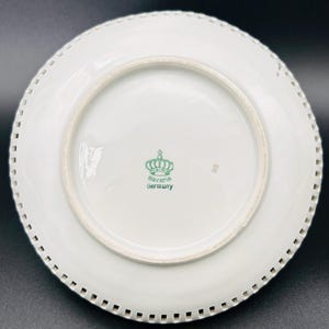 Peut inclure: Assiette en porcelaine blanche avec un bord festonn&eacute;. Le fond de l'assiette porte un logo de couronne verte avec le texte "Bavaria Germany".