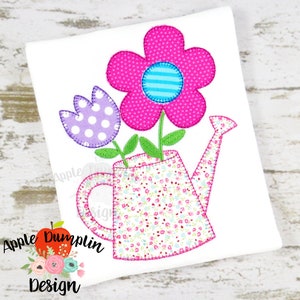 Op de afbeelding: Een roze gieter met een roze bloem en een paarse tulp met witte stippen. De gieter heeft een bloemenpatroon.