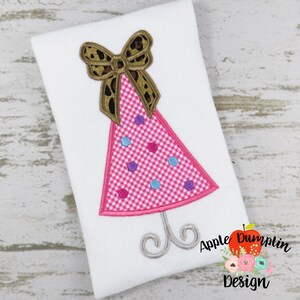 May include: Embroidered design of a pink party hat with a brown leopard print bow on top. The hat has white and pink gingham and blue and purple polka dots. The hat is on a silver stand.