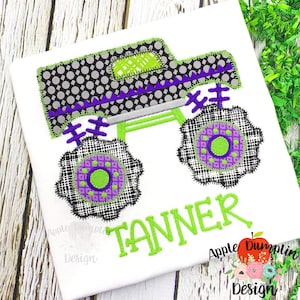 Könnte beinhalten: Grüner, lila und schwarzer Monstertruck-Applikation mit dem Namen Tanner in Grün gestickt. Die Applikation befindet sich auf einem weißen T-Shirt. Das Design stammt von Apple Dumplin Design.
