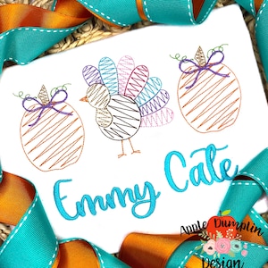 May include: Embroidered design featuring a turkey, two pumpkins, and the name "Emmy Cate" in turquoise thread. The design is on a white fabric background.