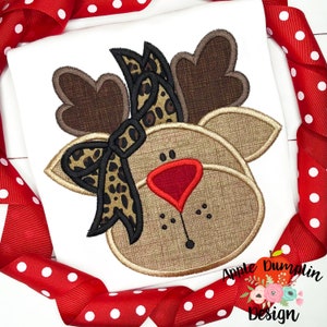 May include: A brown reindeer face with a black and brown leopard print bow. The reindeer has a red nose and brown antlers.