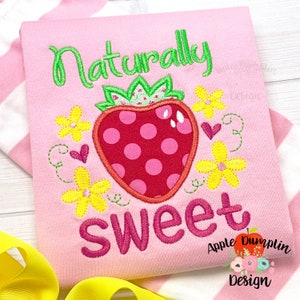 May include: Pink embroidered design with the text "Naturally Sweet" and a red strawberry with green leaves and white polka dots. The design is surrounded by yellow flowers and pink hearts.