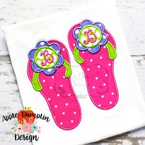 May include: Two pink flip-flop embroidery designs with white polka dots and green straps. Each flip-flop has a purple flower with a green center and a white letter "B" in the center of the flower.