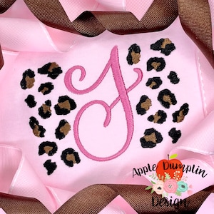 May include: Pink fabric with a large pink letter J and a leopard print design. The text "Apple Dumplin Design" is in the bottom right corner.