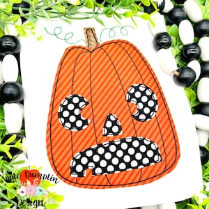 Puede incluir: Un aplique temático de Halloween con una calabaza naranja con ojos y boca de lunares blancos y negros. La calabaza tiene rayas diagonales naranjas y rojas. El diseño incluye vides verdes y el texto "Apple Dumplin Design".
