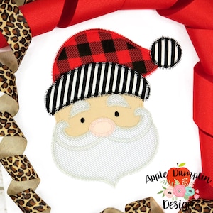 Puede incluir: Diseño de aplique de un rostro de Papá Noel con un gorro de cuadros rojos y negros, una banda de gorro a rayas blancas y negras y una barba blanca. El diseño está contorneado con puntadas blancas.