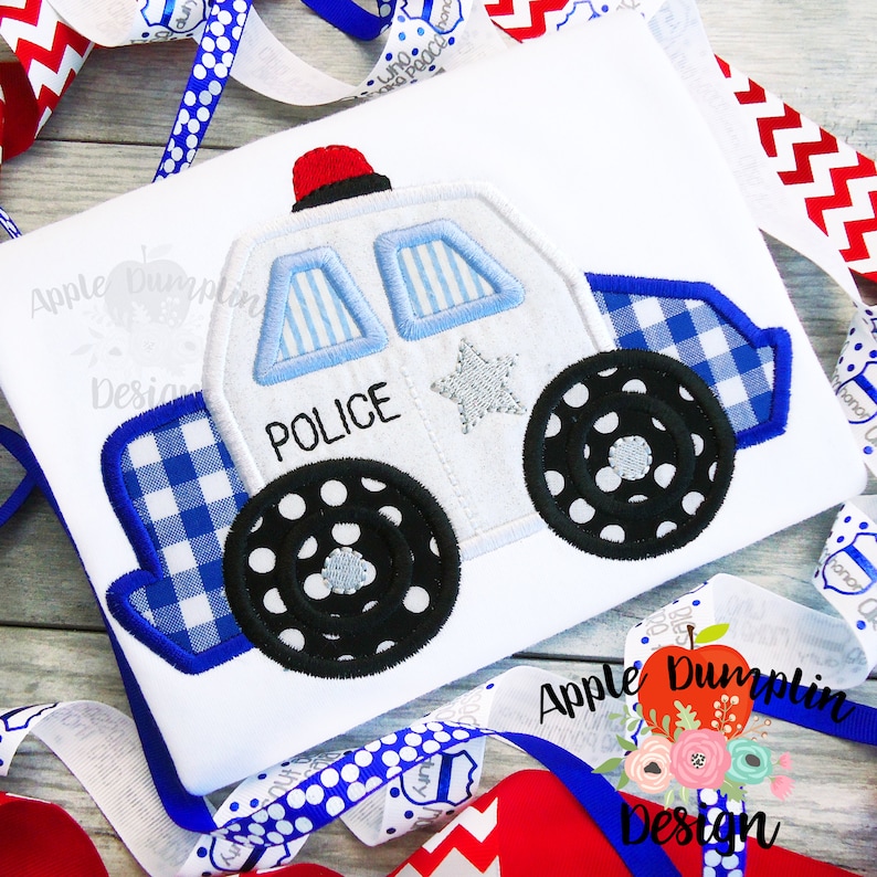 May include: White police car applique with blue and white checkered trim, black wheels with white polka dots, and the word "POLICE" on the side.