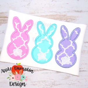 May include: Three embroidered Easter bunny designs in pink, blue, and purple with a white geometric pattern. The bunnies are outlined in white and have a white flower on their tails.