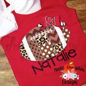 Puede incluir: Camiseta roja y blanca con temática de fútbol con un diseño de fútbol de patchwork, el nombre "Natalie" bordado en negro y el texto "Apple Dumplin Design".