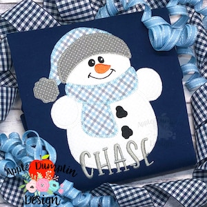 May include: A blue and white snowman applique with a gray hat and scarf. The snowman has black eyes and a carrot nose. The name "CHASE" is embroidered below the snowman.