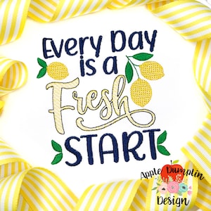 May include: White background with the embroidered text "Every Day is a Fresh Start" in navy blue and yellow. The design includes yellow lemons and green leaves. The image is framed by yellow and white striped ribbon.