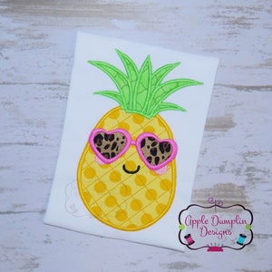 May include: A yellow pineapple with a green leafy top and pink heart-shaped sunglasses with a leopard print pattern. The pineapple has a smiling face.