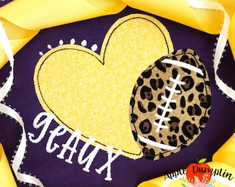 May include: Purple fabric with a yellow heart and a brown and white football with a leopard print design. The text "geaux" is embroidered in white below the heart.