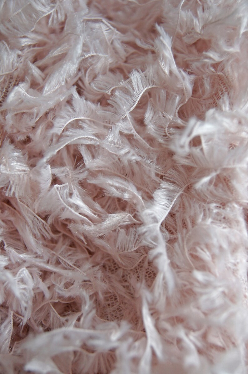 May include: Close-up of a soft, pink fabric with a fluffy, feathery texture. The fabric has a delicate, almost translucent quality.