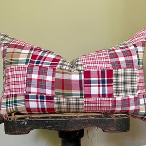 May include: A patchwork pillow with red, green, blue, and white plaid fabric squares. The pillow is sitting on a wooden stool.