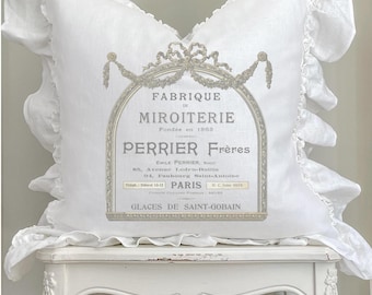 May include: White pillow with a ruffled edge and a vintage-style print of a French mirror shop called "Fabrique de Miroiterie Perrier Frères" founded in 1863. The print includes the shop's address and the words "Glaces de Saint-Gobain".