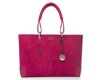 May include: A pink cork tote bag with a silver charm and a brown leather strap. The bag has a textured cork surface.