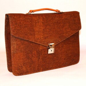 May include: A brown leather briefcase with a metal clasp. The briefcase has a top handle and a flap that closes with a metal clasp.